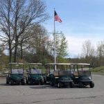 Golf carts parked in front of a flag pole with an American flag, at Widow's Walk Golf Course in Scituate, Massachusetts